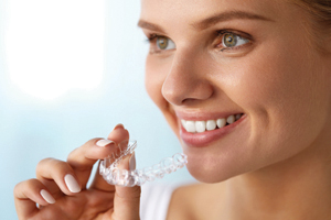 Close up of smiling female Dental Patient inserting her Invisalign Clear Braces