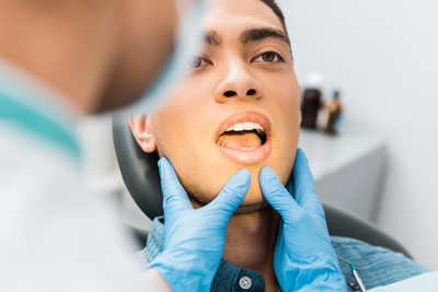 male dental patient with open mouth receiving general dental exam